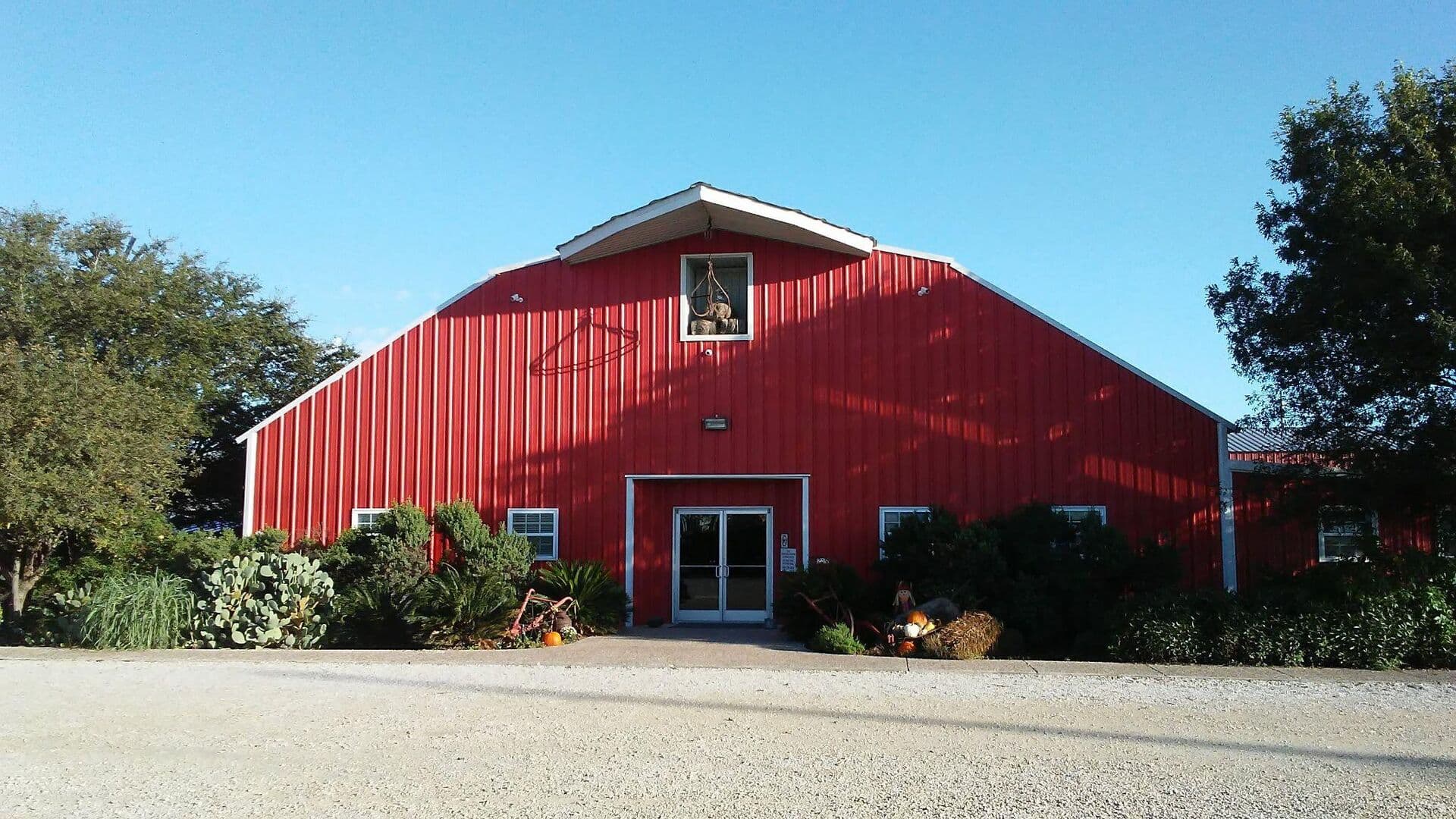 The Big Red Barn in Seguin, a red barn with white trim under a clear blue sky