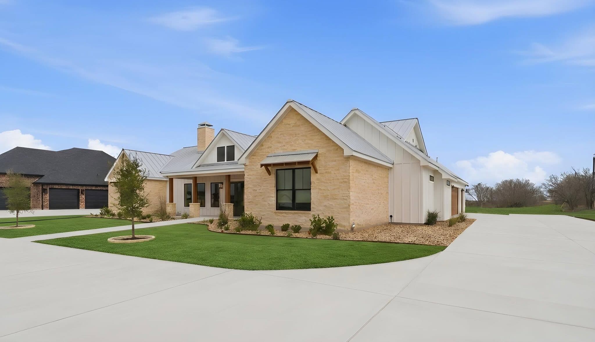 A finished Pioneer Landscapes install at a new custom home in Seguin: sod lawn, tree wells, and a gravel bed with new plantings against limestone