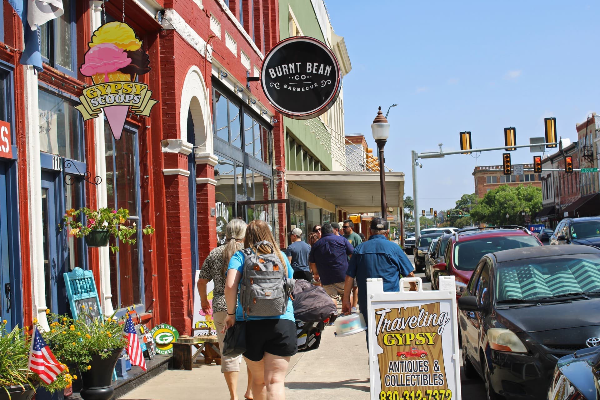 A weekend sidewalk crowd outside shops and barbecue in downtown Seguin