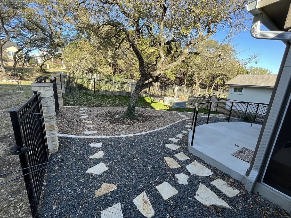 A flagstone stepping path set into two-tone gravel with curved limestone edging and a preserved oak, on a finished Pioneer Landscapes install