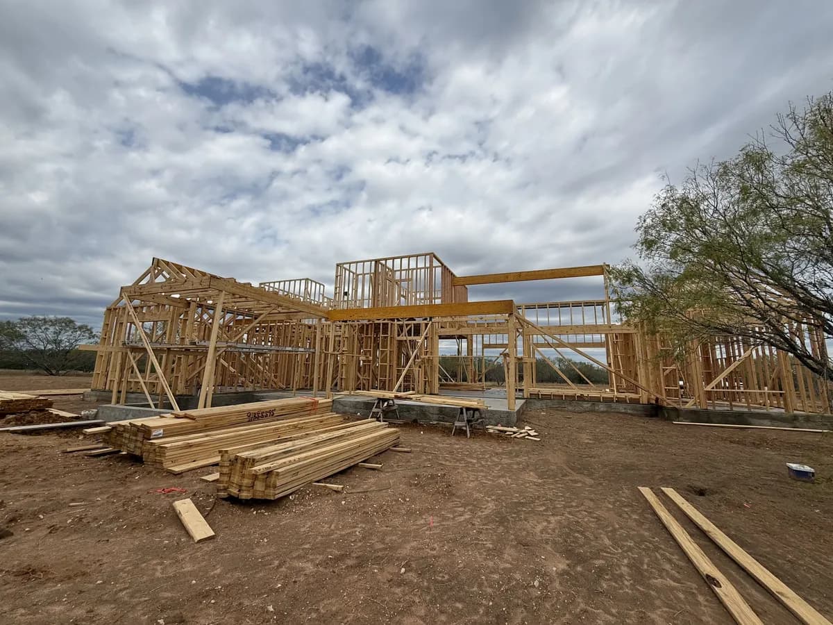House framing on a TKG jobsite under a big cloudy Texas sky